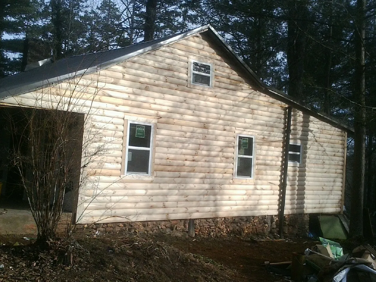 New log siding and dark metal roofing on a gable end in Sumiton
