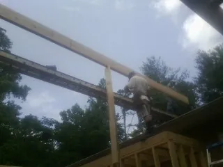 Carpenter setting a ridge beam over a new addition frame — Ice Dam Removal by Roofing Brothers in Sumiton