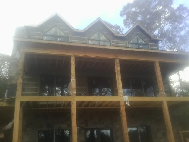 Dormers and porch framing on a large log home under construction — Roof Coating work by our crew in Sumiton