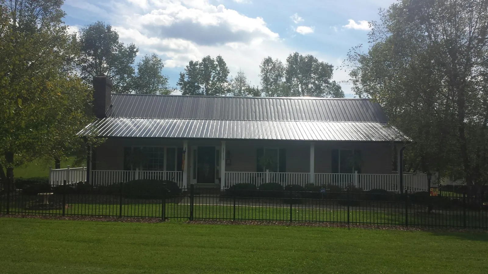 Gray metal roof on a brick ranch with a full width front porch — Gutter Guard Installation work by our crew in Sumiton