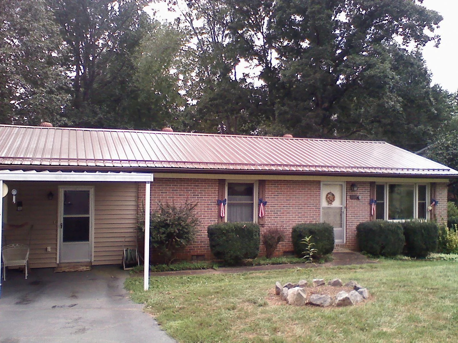 Bronze metal roof and carport on a brick ranch home — Roof Repair work by our crew in Sumiton